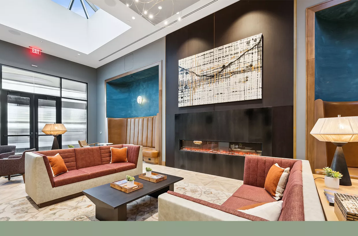 Modern lounge with red sofas, fireplace, abstract art, and skylight ceiling